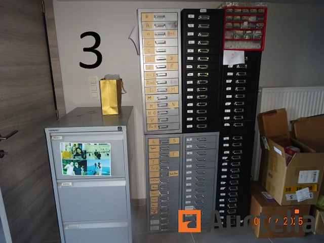 1 set van 4 zwarte kleur ladekasten hoogte 27/40/60, gevuld met reserve stukken voor storm merk horloges, 3 grijze kleur ladekasten, 1 rode pvc ladedoos, 1 metaal kast met drie grijze lades met hangende rugleuningen - afbeelding 9 van  18