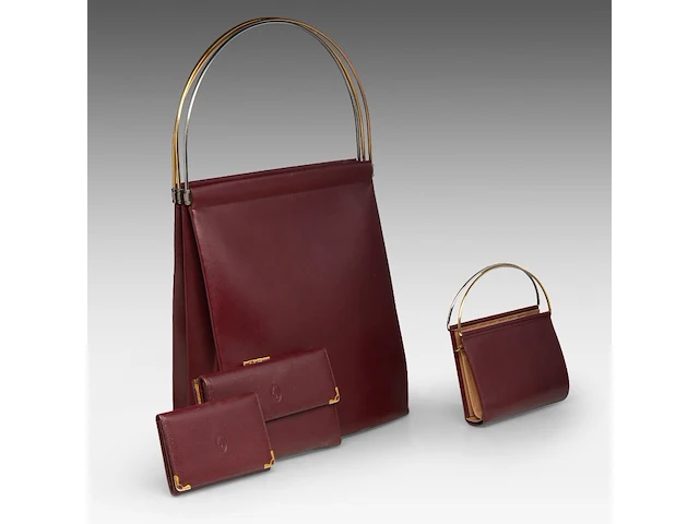 A cartier burgundy 'trinity' top handle bag, wallet and two 'must de cartier' wallets - afbeelding 1 van  16