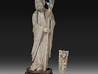 A chinese ivory sculpture of a sage leaning on his kirin-shaped staff, with a small double gourd hanging from it, added a ditto sculpture of a lady laying down with a child, late qing dynasty (1644-1912), total h 30 cm -