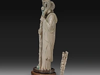 A chinese ivory sculpture of a sage leaning on his kirin-shaped staff, with a small double gourd hanging from it, added a ditto sculpture of a lady laying down with a child, late qing dynasty (1644-1912), total h 30 cm - - afbeelding 3 van  7