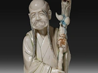 A chinese ivory sculpture of a sage leaning on his kirin-shaped staff, with a small double gourd hanging from it, added a ditto sculpture of a lady laying down with a child, late qing dynasty (1644-1912), total h 30 cm - - afbeelding 6 van  7