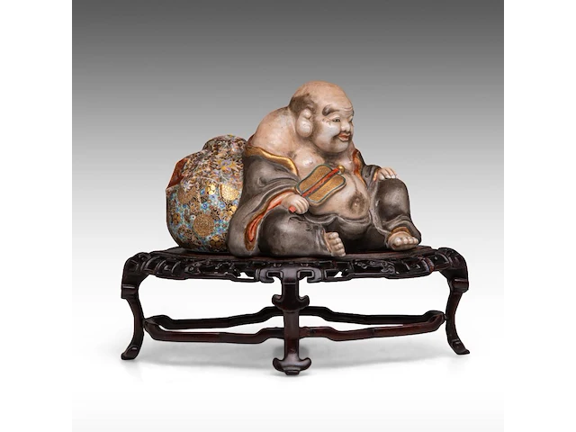 A finely painted japanese polychrome porcelain figure of hotei leaning against the bag of good fortune, l 22 cm - figure h 14,5 cm - total h 22,5 cm - afbeelding 1 van  8