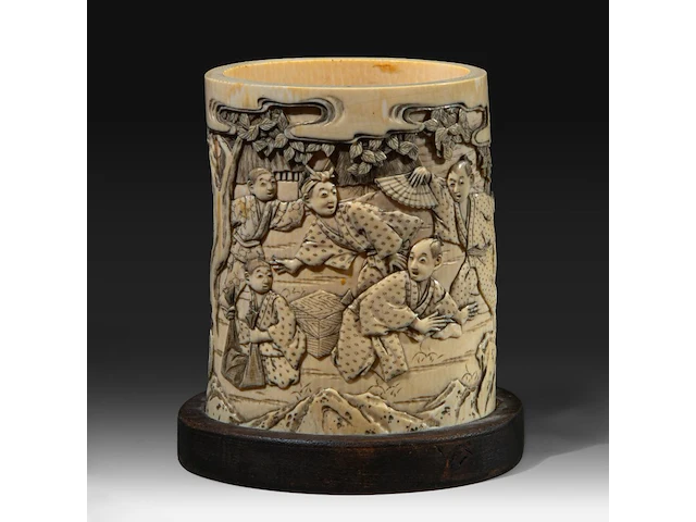 A japanese ivory brushpot, carved with figures in a landscape playing a game, meiji period (1868-1912), total h 14 cm - w 13 cm - d 10 cm (+) - afbeelding 1 van  7