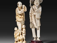 A japanese ivory okimono of a man with his two sons collecting eggs, signed, meiji period (1868-1912), h 26 cm - 757g, added; a chinese ivory sculpture of a man with fishing gear, late qing dynasty, total h 30 cm - ivory