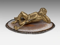 A paperweight of a brass monkey smoking its pipe and lying on the intersection of a mineral stone, ca. 1900 5 x 15 cm. (1.97 x 5.91 in.)