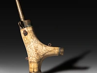 A renaissance deer horn gunpowder flask, with carved decoration of a satyr having an erection, ca. 1550 23 x 10.5 cm. (9.06 x 4.12 in.)