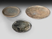 A set of three mesopotamian well-patinated schist and stone plates, syria, circa 2000-1000 bce (+)