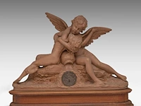 A terracotta mantle clock with amor and psyche, signed roberto aurilli 48 x 70 cm. (18.89 x 27.55 in.), with wooden base 59 x 75 cm. (23.23 x 29.53 in.)