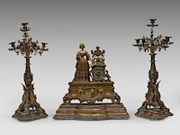 A three-piece eclectic gilt metal mantel clock set, with on top louise marie of orléans, queen of the belgians, mid 19thc the clock 45 x 43 cm. (17.71 x 16.92 in.), the candelabra: 66 cm. (25.98 in.)