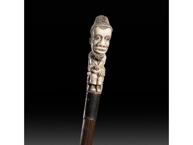 A walking stick with ivory handle of an african man masturbating with an extendible penis, english, ca. 1900, total h 94 cm - ivory h 11,5 cm - ivory w 3 cm - total weight 303g (+) - afbeelding 1 van  5