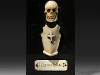 An ivory memento mori sculpture of a skull and armour with a nameplate '21 cromatella j.', 19thc, fixed on a stone plaque, h 14 cm - w 8 cm (+)