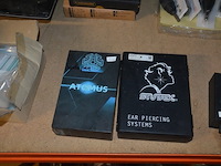 Doosje met ca. 80 stuks piercings en stretchers, ca. 36 metalen verstelbare tatoeage handvaten, elektrische tatoeage machine goud rotary, 2 spoel tatoeage machines,10 wergwerp cartridges grip zwart, 2 paarse bischop rotary tatoeage machines, - afbeelding 30 van  33