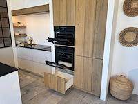 Exclusieve landelijk-moderne maatkeuken in u-opstelling met granieten werkblad en aeg-inbouwtoestellen - afbeelding 15 van  20