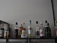 Lot diverse aangebroken flessen sterke drank (o.a. eristoff, martini, campari), rode wijn (caitel), siropen (o.a. monin)