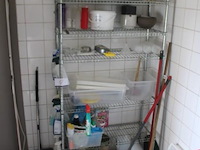 Metalen opbergrek met diverse schoonmaakartikelen, emmers en toebehoren