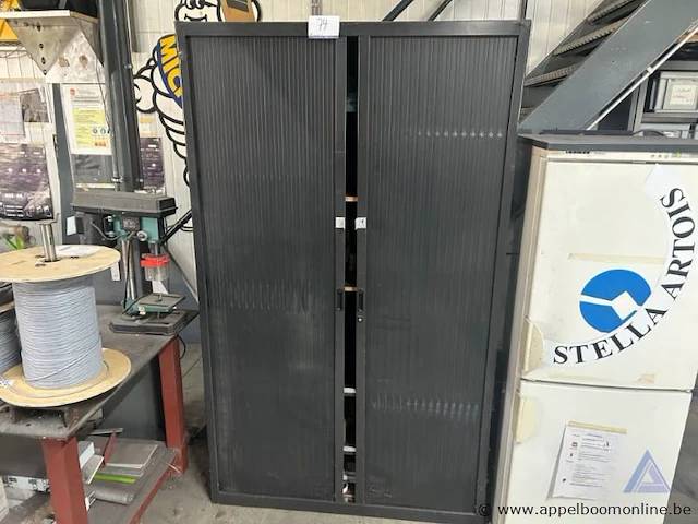 Metalen roldeurkast. de kast is gevuld met diverse materialen, waaronder elektriciteitscomponenten, kabels, tapes en kleine gereedschappen. - afbeelding 1 van  3