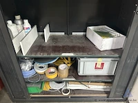 Metalen roldeurkast. de kast is gevuld met diverse materialen, waaronder elektriciteitscomponenten, kabels, tapes en kleine gereedschappen. - afbeelding 3 van  3