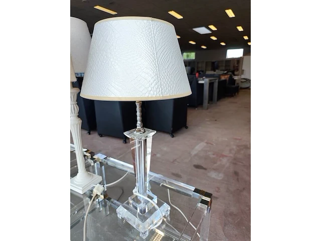Moderne tafellamp met helder acryl middenstuk en beige stoffen lampenkap riviera maison, moderne tafellamp met kristallen lampenvoet en witte lampenkap met slangenleerstructuur, klassieke tafellamp in oudwit met gedraaide houten voet en beige stoffen kap - afbeelding 2 van  8
