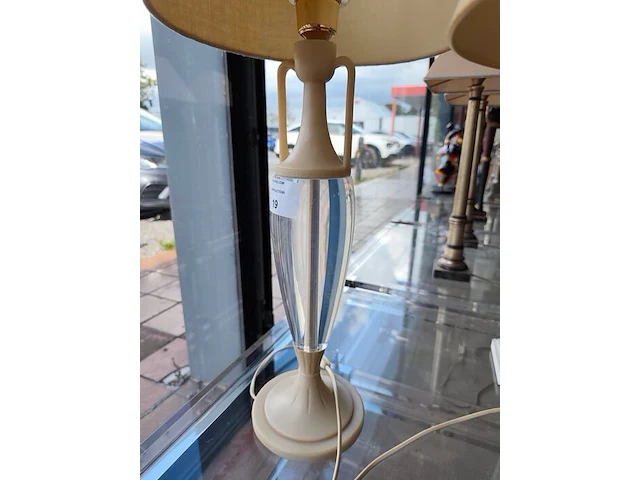 Moderne tafellamp met helder acryl middenstuk en beige stoffen lampenkap riviera maison, moderne tafellamp met kristallen lampenvoet en witte lampenkap met slangenleerstructuur, klassieke tafellamp in oudwit met gedraaide houten voet en beige stoffen kap - afbeelding 6 van  8