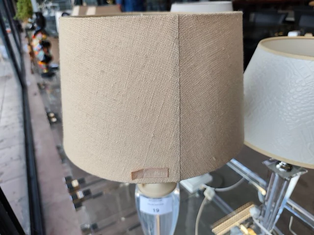 Moderne tafellamp met helder acryl middenstuk en beige stoffen lampenkap riviera maison, moderne tafellamp met kristallen lampenvoet en witte lampenkap met slangenleerstructuur, klassieke tafellamp in oudwit met gedraaide houten voet en beige stoffen kap - afbeelding 7 van  8