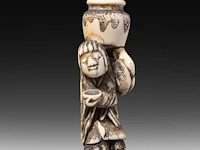 Two japanese ivory netsuke, one of a woman carrying a large jug, signed masakazu, the other of a resting man, edo/meiji period (19thc), h 6 cm - 15,9g / h 2 cm - 14g (+) - afbeelding 3 van  7