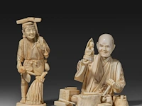 Two japanese walrus ivory okimono of a farmer with a pipe and another of a sculptor inspecting a finished piece, meiji/taisho period (first half of the 20thc), h 14 cm / h 11,5 cm (*)
