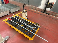 Werkplaatsgereedschap op gele opvangbak – smeerpistool, sproeitoestel en metalen staven - afbeelding 1 van  3